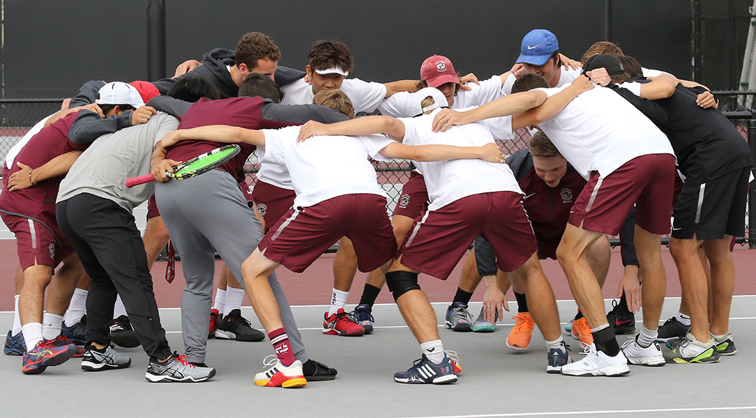 The men's tennis team huddles.