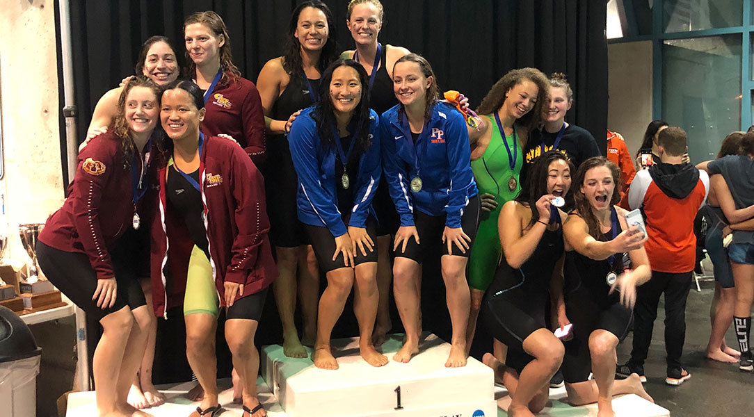 The women's 400 relay team poses on the podium.