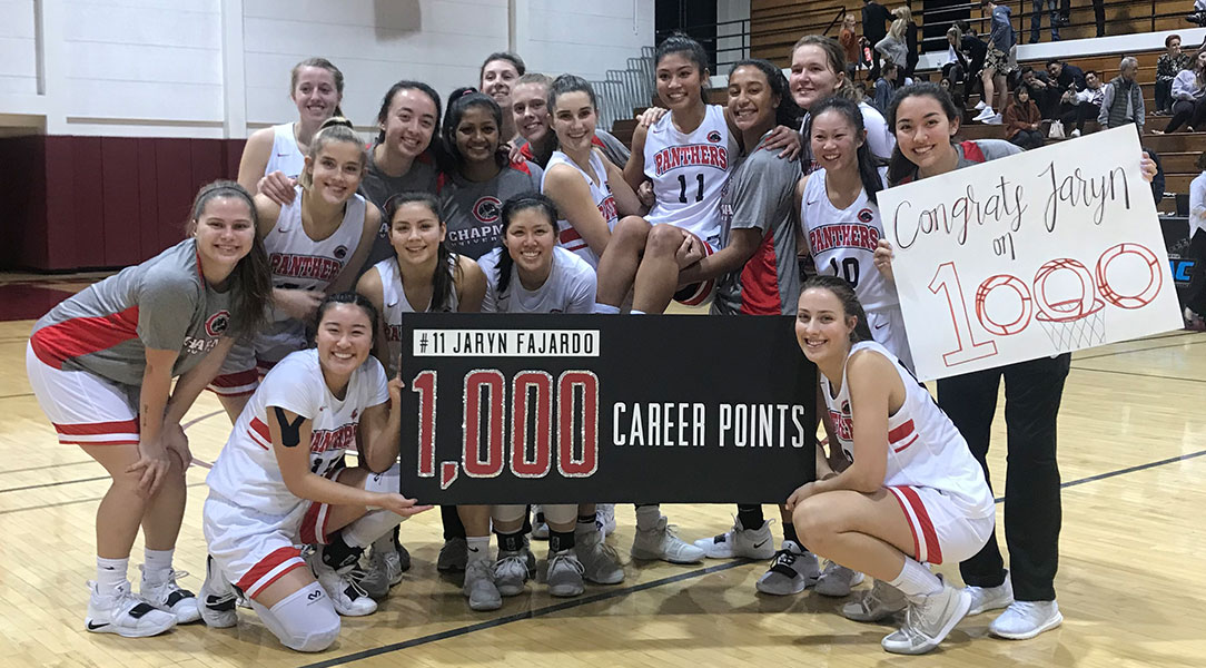 The women's basketball team poses with Jaryn Fajardo to celebrate scoring her 1,000th point.