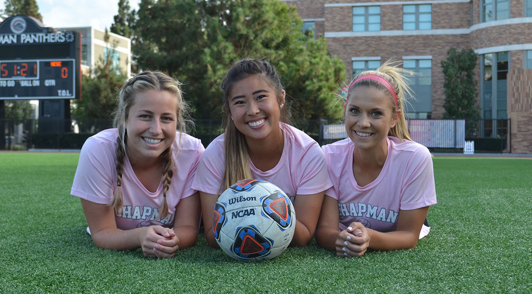 Women's soccer seniors Shelby Brown, Megan Kawakami and Lindsay Erl pose with a soccer ball.