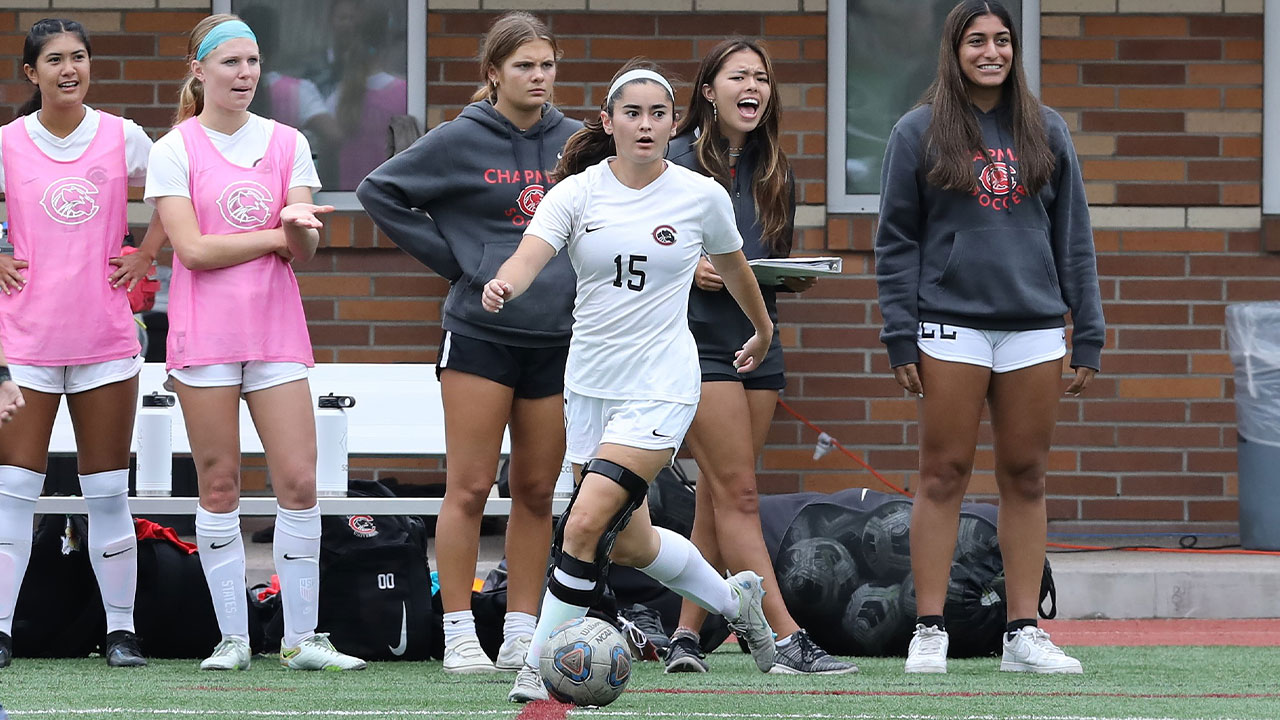 Shannon Coyle with the soccer ball in front of her bench looking to make a pass.