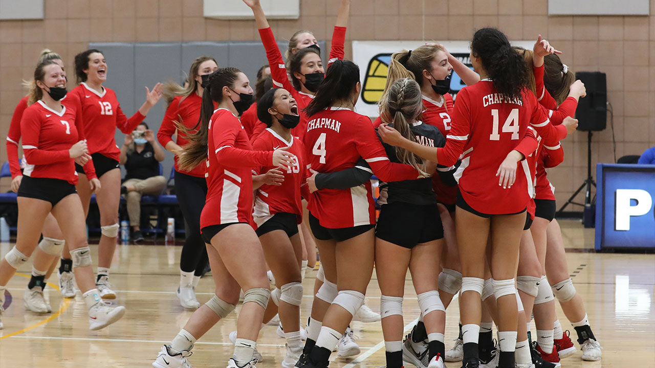 The volleyball team celebrates on the court after the win.