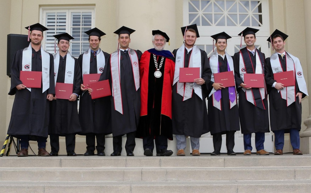 The eight baseball graduates with President Struppa.