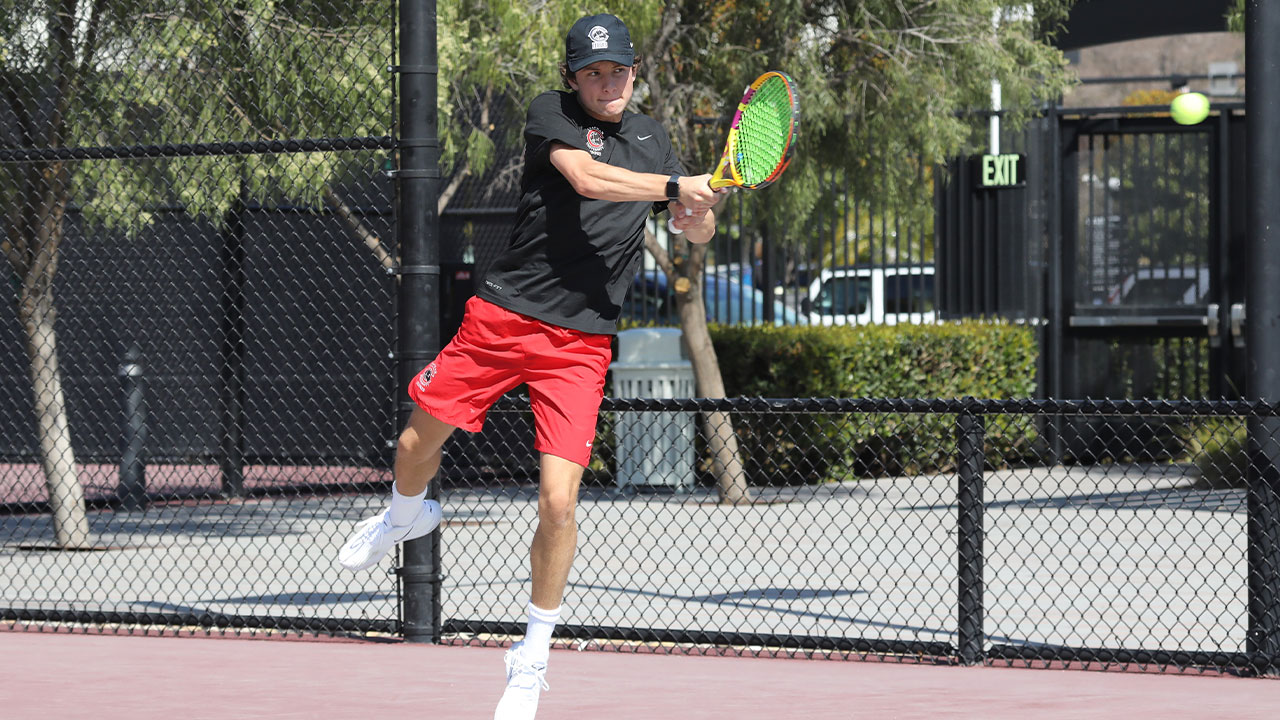 Mac Caldwell hits a tennis ball from the baseline of the court.