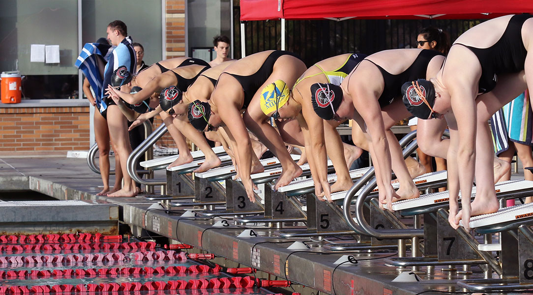 Women's swimmers get ready on the blocks.