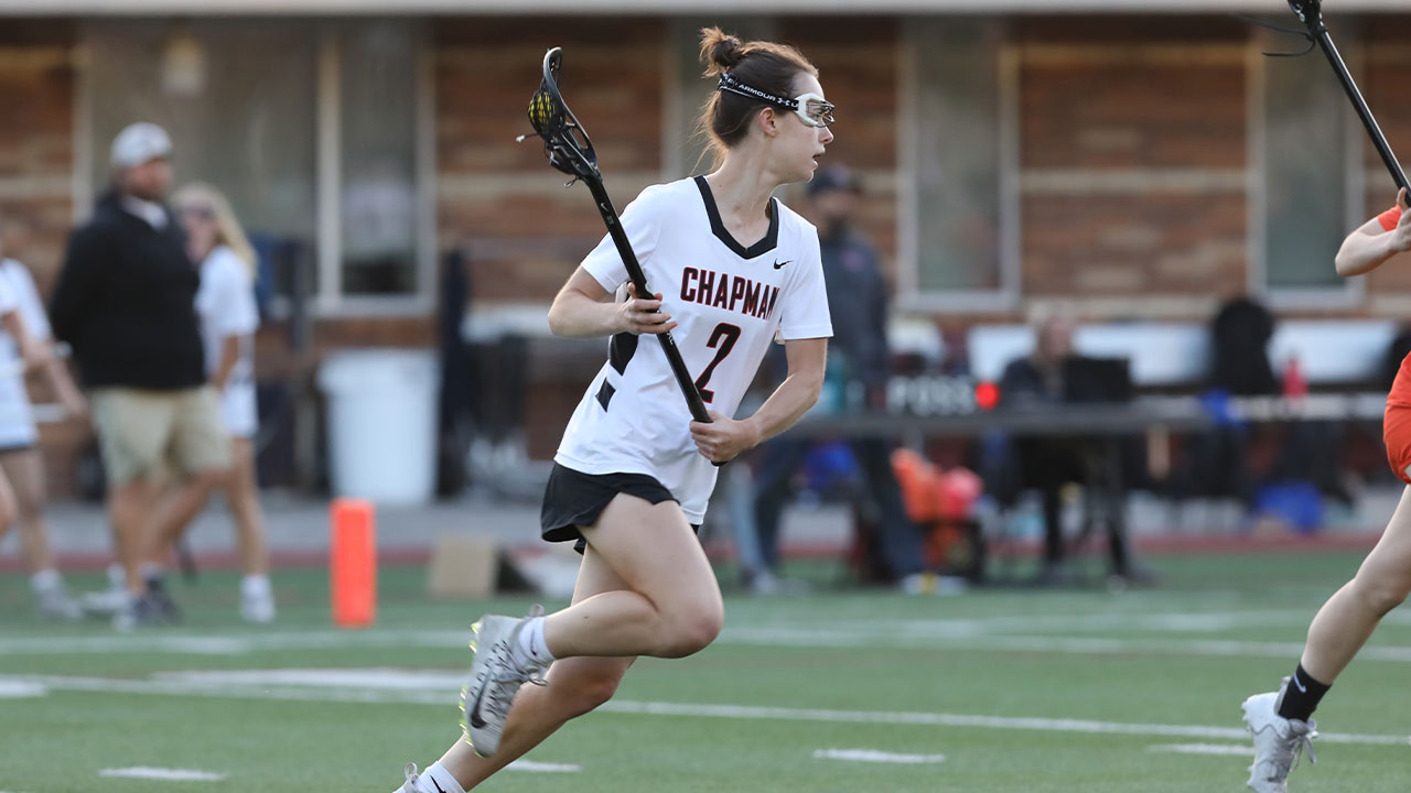 Anna Klose running down the field carrying the ball in her lacrosse stick.