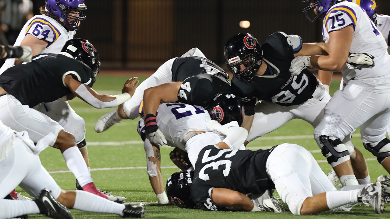 Chapman defenders tackle a Cal Lutheran running back.