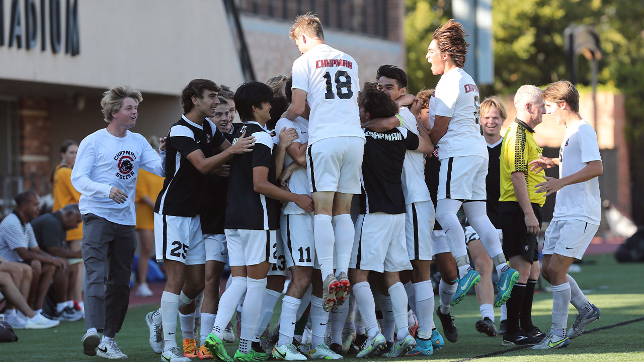 The men's soccer team celebrates a goal scored with two jumping in the air.