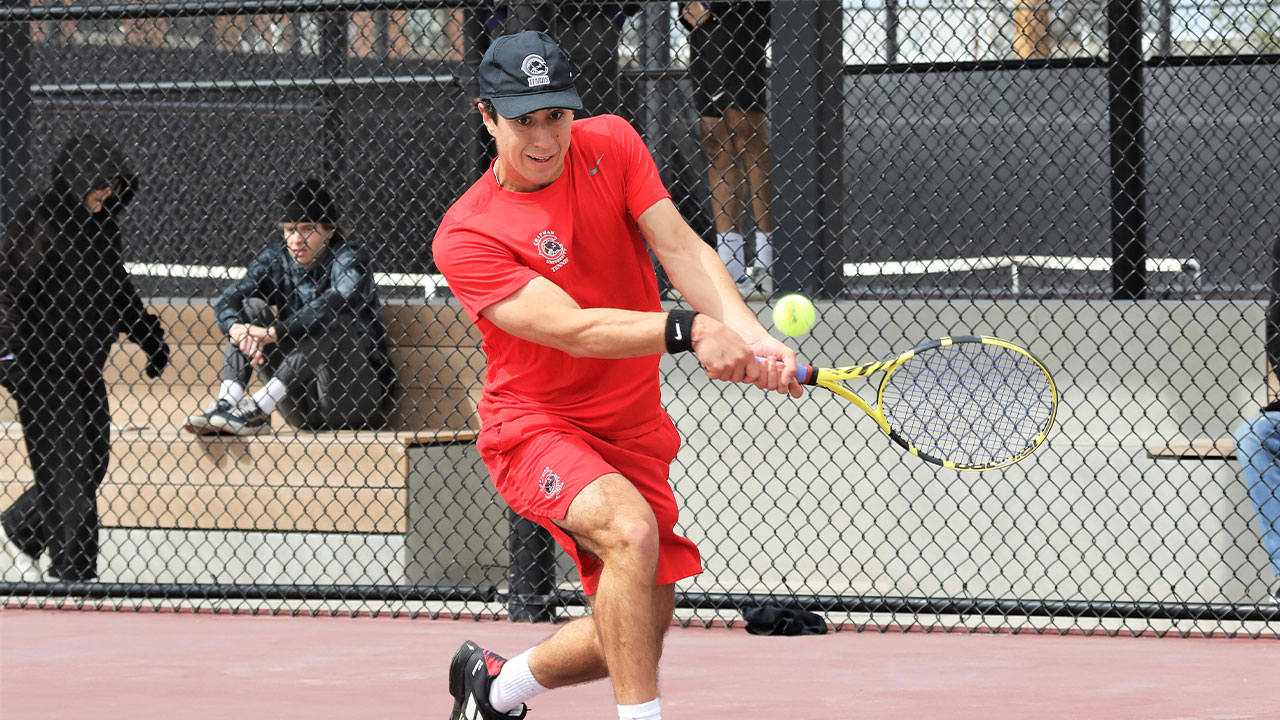 Tommy Hays hitting a back hand shot playing tennis.