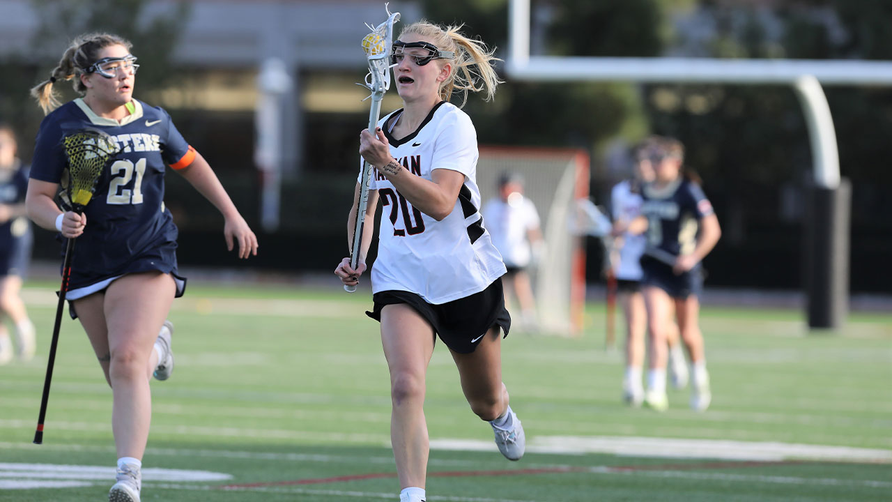 Annika Carlson runs away from the defender carrying the lacrosse ball. 